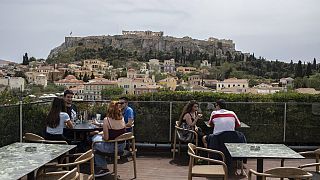 People sit in on a cafe terrace, in the Monastiraki district of Athens