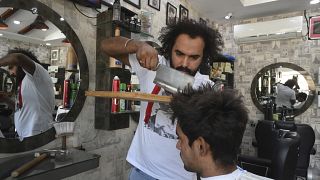 Pakistani barber Ali Abbas uses a butcher knife to cut the hair of a customer at his shop in Lahore.