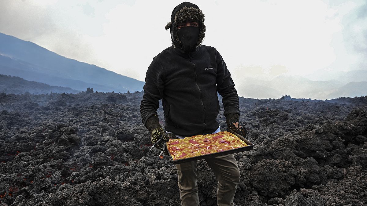 David Garcia checks a pizza he's cooking on the lava rivers that come down from the Pacaya volcano.
