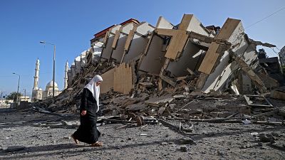 A Palestinian woman walks past a destroyed building in Gaza City.