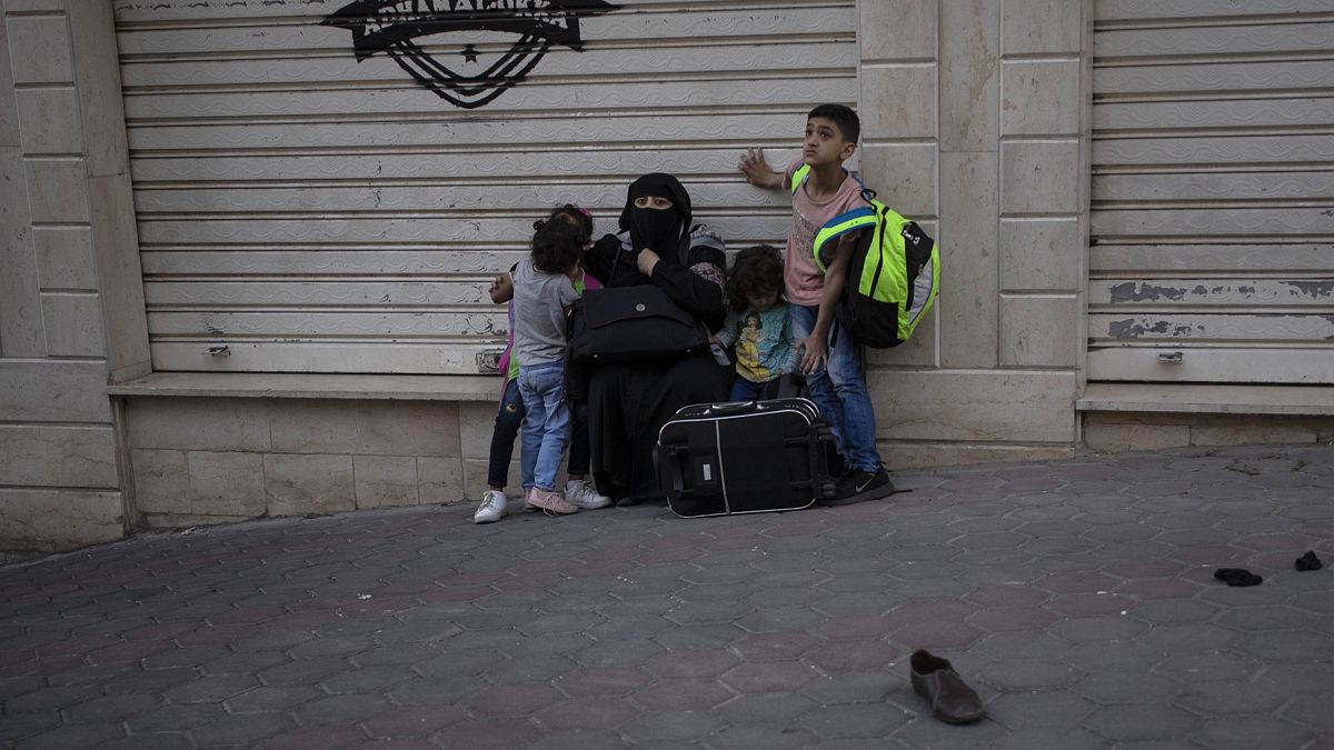 İsrail'in Gazze'ye yönelik hava bombardımanında evleri bombalanan bir aile, yol kenarında beklerken