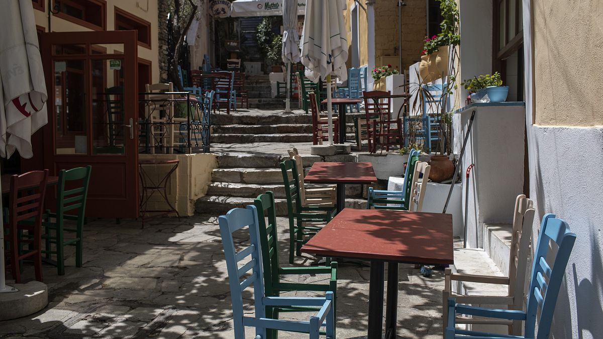 Chairs with a seat removed are placed around tables at a closed restaurant in the Athens' historic Plaka district, on Friday, April 30, 2021