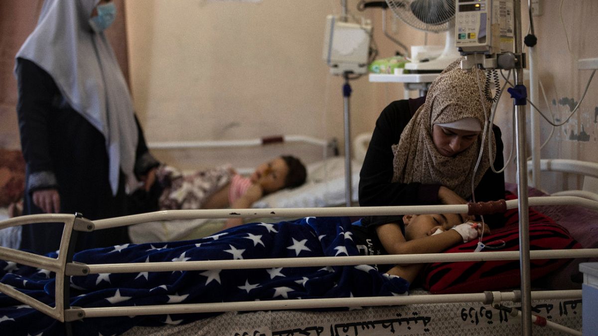 The mother of Yazan Al-zaharna, 9, comforts him as he rests at the Shifa hospital in Gaza City, Thursday, 13 May, 2021.