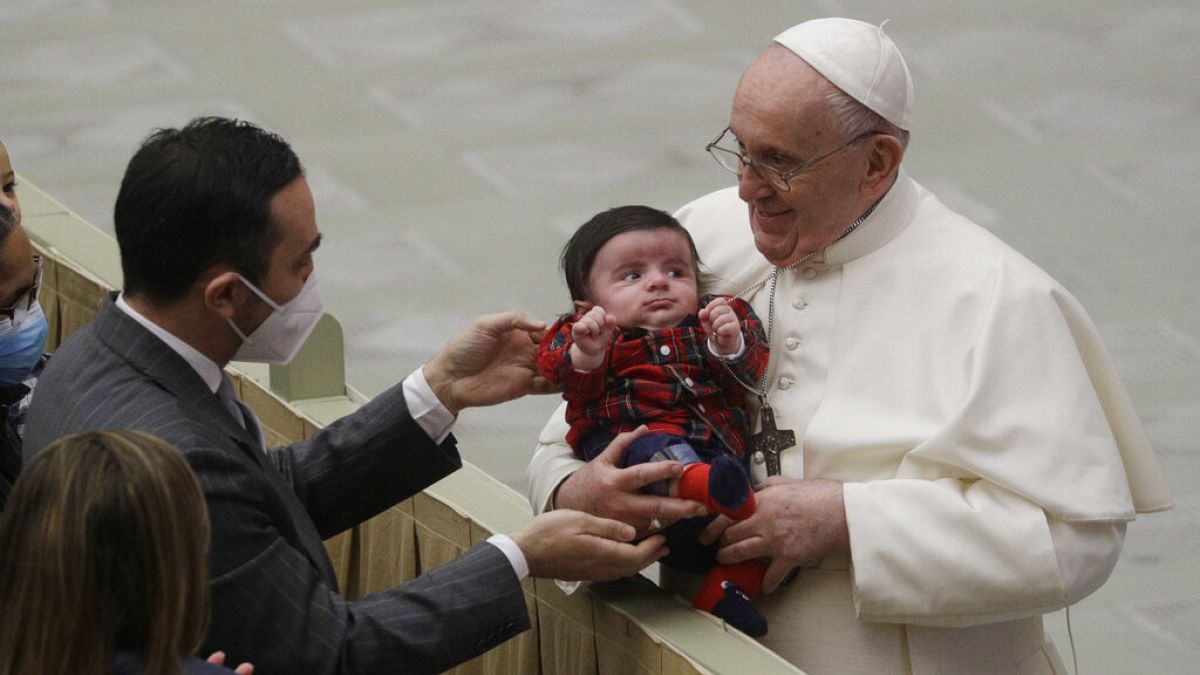 Pope Francis cuddles a baby as he exchanges holidays greeting with Vatican employees in December 2020