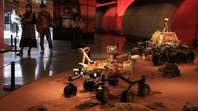 Visitors pass by an exhibition depicting rovers on Mars in Beijing on Friday, May 14, 2021.