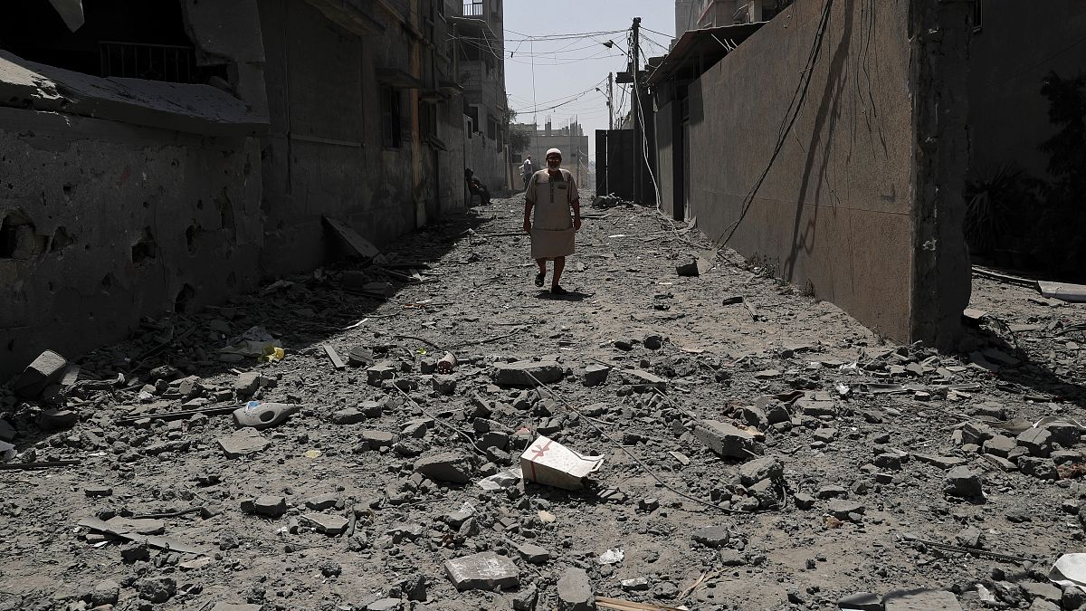 رجل يمشي فوق ركام مبنى دمره القصف الإسرائيلي  