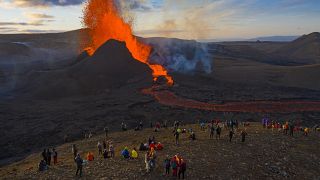 People watch as lava flows from an eruption from the Fagradalsfjall volcano on the Reykjanes Peninsula in southwestern Iceland on Tuesday, May 11, 2021. 