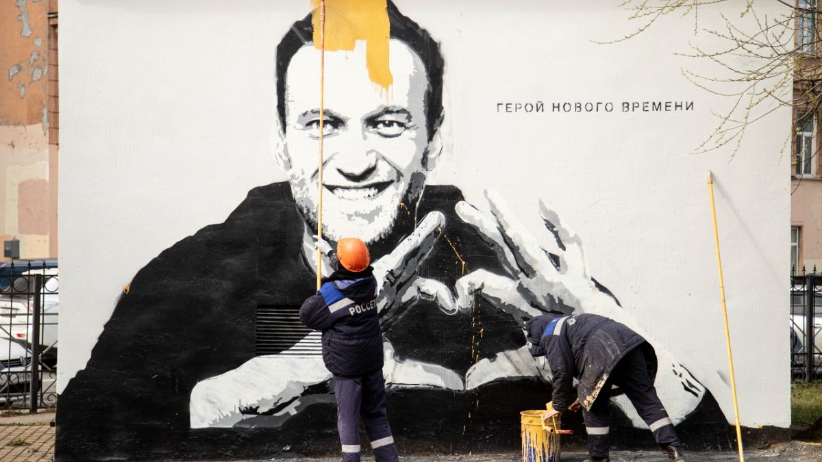 عمال البلدية يزيلون رسماً جدارياً يظهر فيه نافالني، في سانت بطرسبرغ 28 أبريل 2021