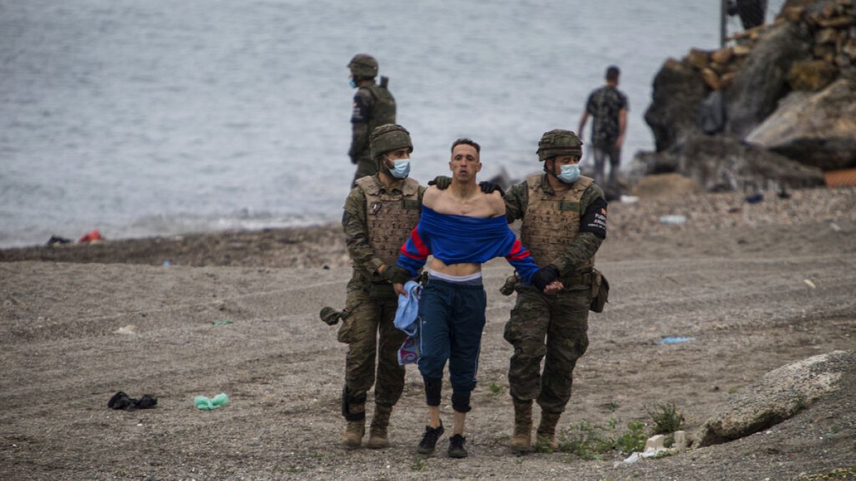 A man from Morocco is detained by soldiers of the Spanish Army at the border of Morocco and Spain, at the Spanish enclave of Ceuta, on Tuesday, May 18, 2021