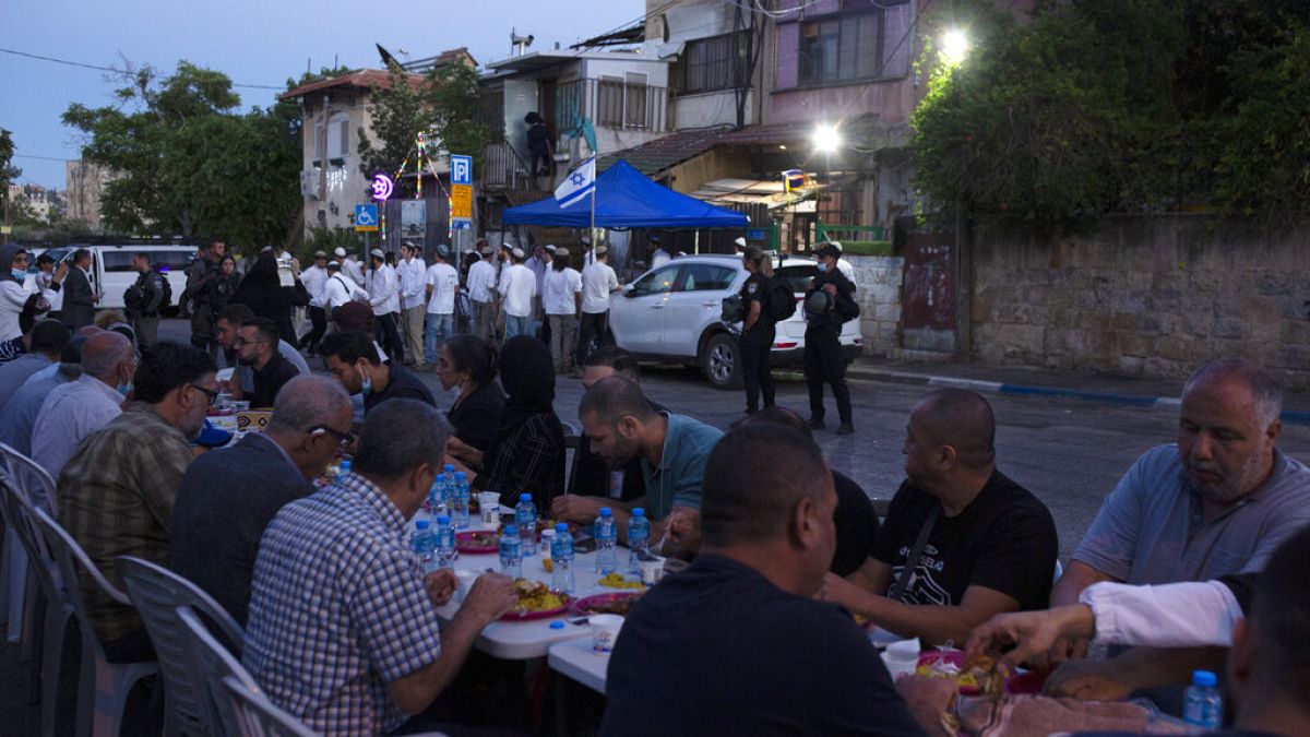  maggio 2021: a Sheikh Jarrah un gruppo di palestinesi rompe il digiuno di Ramadan sotto lo sguardo dei coloni e della polizia israeliana 