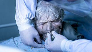 A medic wearing a special suit against coronavirus adjusts a coronavirus patient's oxygen mask at the intensive care unit at a hospital in the mining town of Selydove, Ukraine