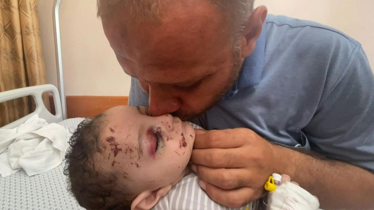 يحتضن محمد الحديدي طفله الرضيع عمر داخل مستشفى في غزة الناجي الوحيد من الغارات الجوية الإسرائيلية.