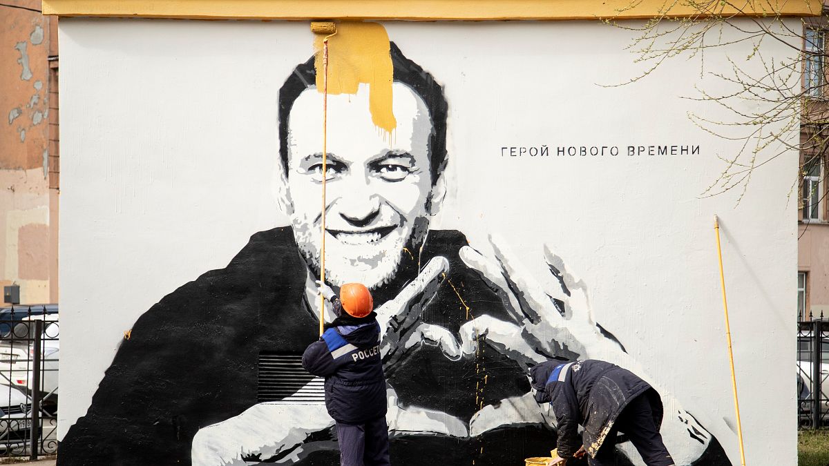 A painting of Russia's imprisoned opposition leader Alexei Navalny is painted over by municipal workers in St. Petersburg