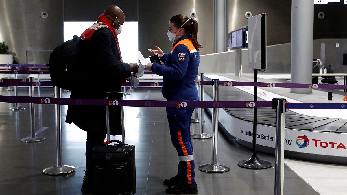 A member of Civil Protection checks air travellers documents at Paris Charles de Gaulle airport