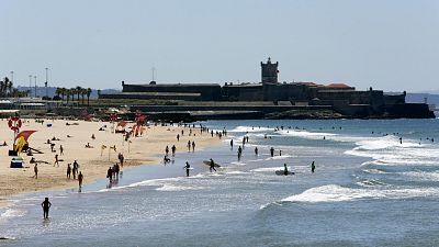 People walk along Carcavelos beach near Cascais, outside Lisbon.