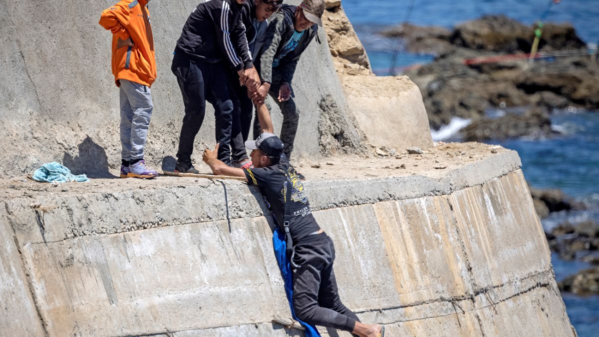 مهاجرون قاصرون يتسلقون جدارًا بحريًا في مدينة الفنيدق الشمالية بعد محاولتهم عبور الحدود من المغرب إلى جيب سبتة الإسباني في شمال إفريقيا في 19 مايو 2021.