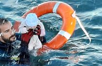 a member of the civil guard rescues a baby that was separated from its migrants parents, Spain