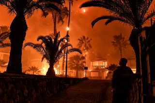 A man stands in front of a wild fire in Schinos, west of Athens, Greece. May 19, 2021