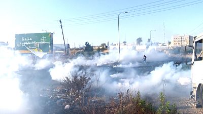 Tear gas canisters fired by Israeli forces landing on Palestinians during a protest near the DCO checkpoint, north of Ramallah