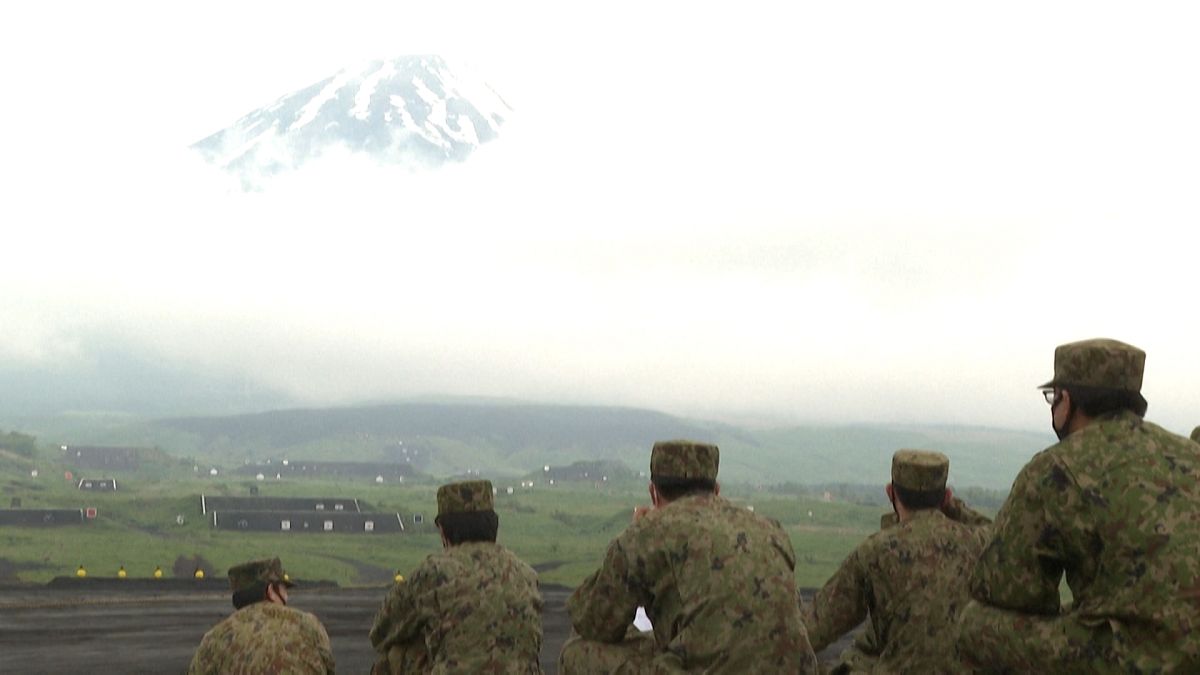 Members of self-defence forces watching exercises with Mount Fuji in the background