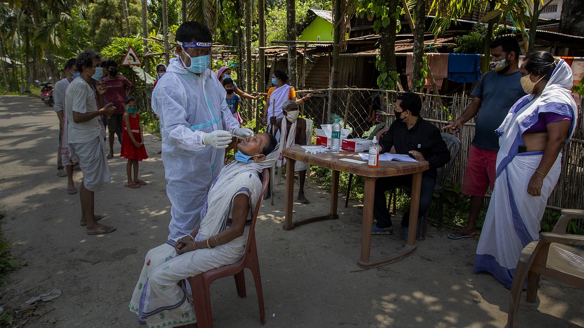 An Indian health worker in protective suit takes the swab of a village woman to test for COVID-19 in Burha Mayong village, Morigaon district of Assam, India, May 22,