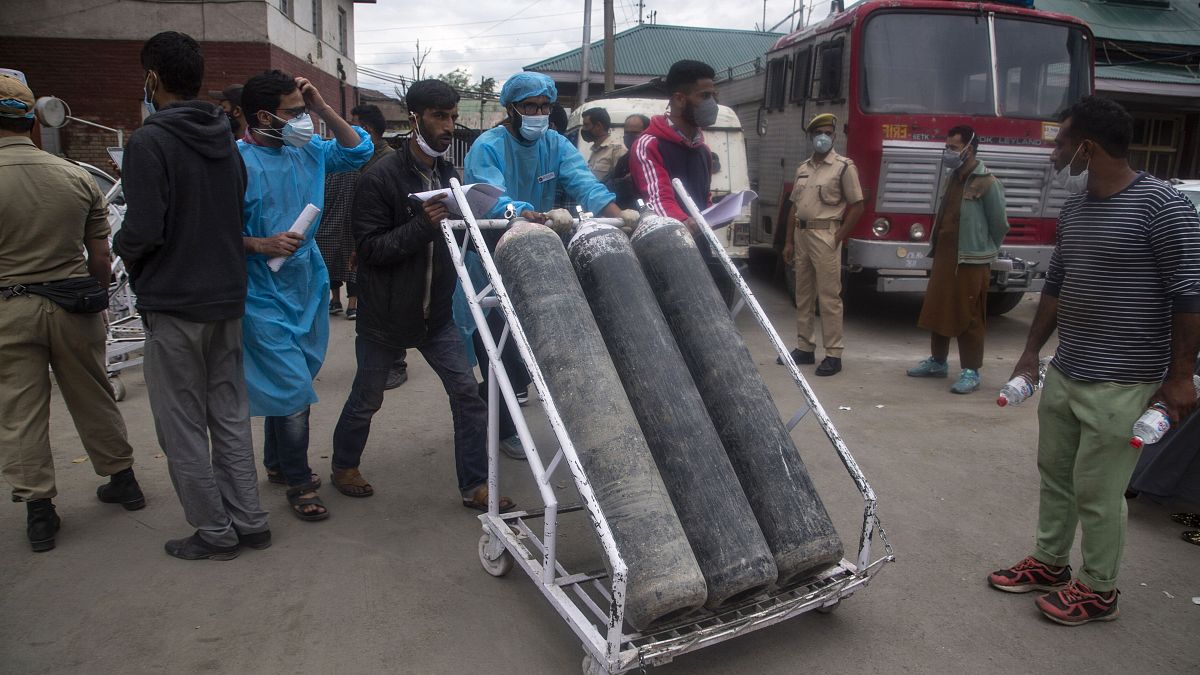 Local men hired by administration assist transport of oxygen cylinders in the premises of a hospital in Srinagar, Indian controlled Kashmir, Sunday, May 23, 2021. 