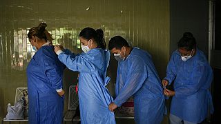 Government doctors put on protective gowns as they prepare to give free, rapid COVID-19 tests to residents who volunteer in the El Paraiso neighborhood of Caracas, Venezuela