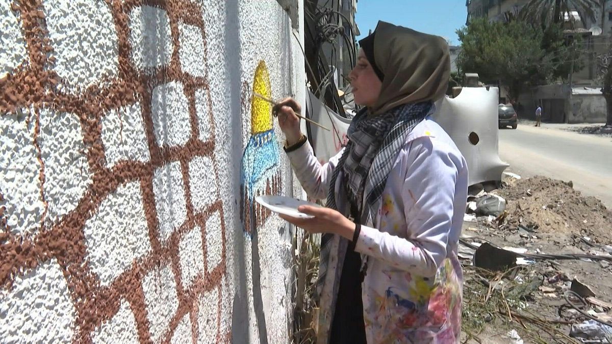 فنانة فلسطينية ترسم على جدران مهدمة في غزة بعد القصف الإسرائيلي على القطاع المحاصر