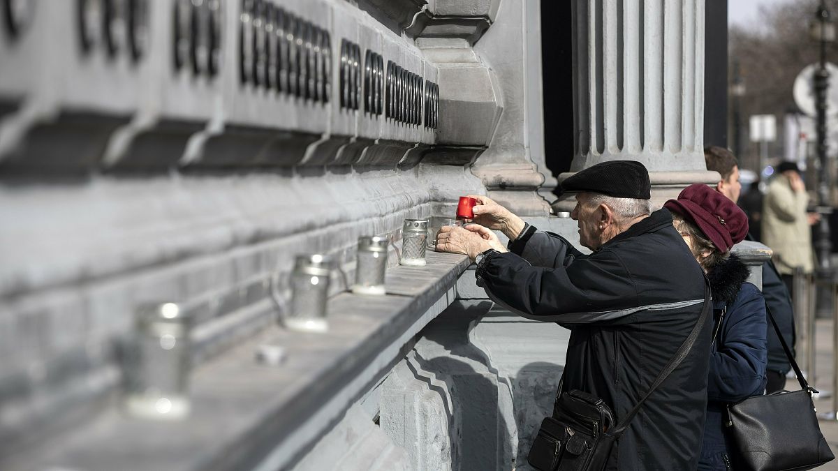 Elderly people light candles at the Wall of Heroes outside the House of Terror Museum to pay their tribute on the occassion of the Memorial Day of Victims of Communism.