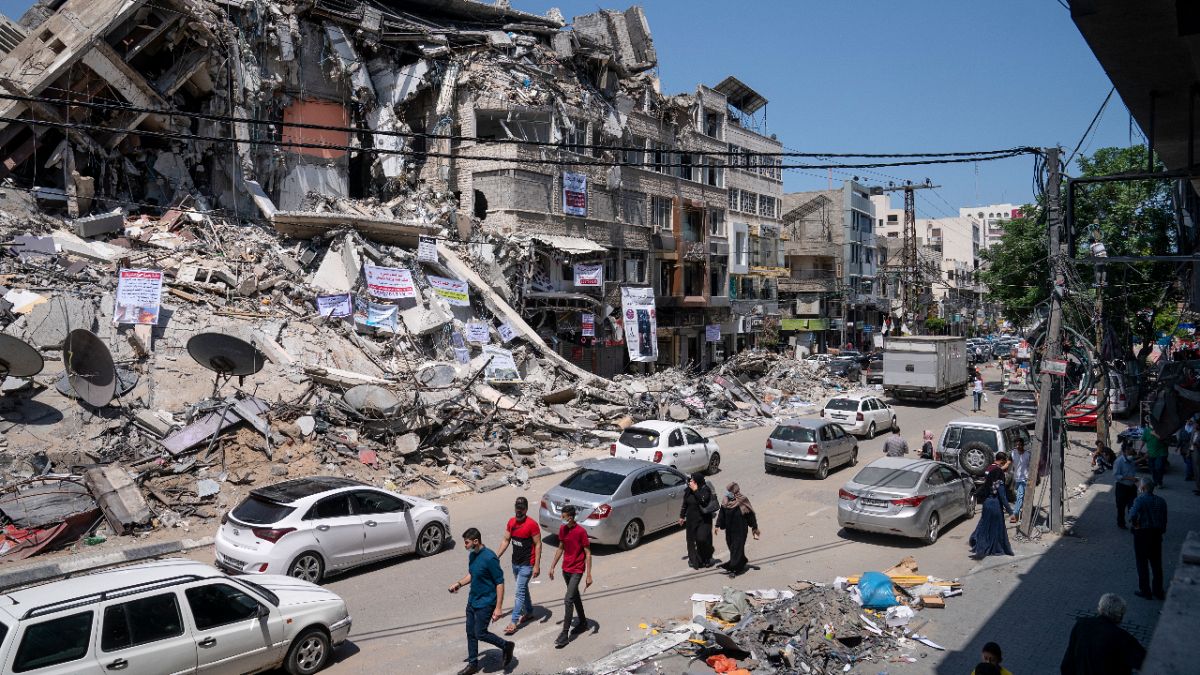 Motorists and pedestrians move past a building destroyed by an air-strike prior to a cease-fire between Gaza's Hamas rulers and Israel, Tuesday, May 25, 2021, in Gaza City.