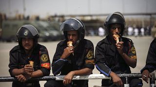 عناصر الشرطة المصرية بأكلون المثلجات أثناء حراسة محيط محكمة في القاهرة. 2012/05/02