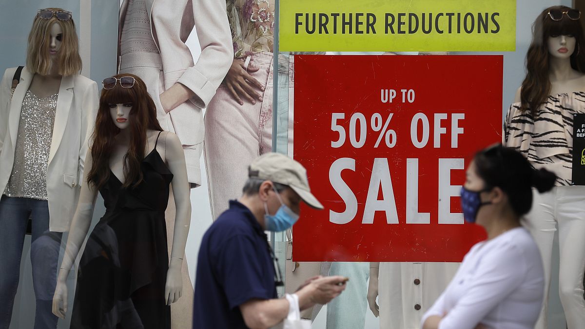 Shoppers pass a sale sign in a shop window on Oxford Street in London, Aug. 13, 2020. 