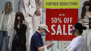 Shoppers pass a sale sign in a shop window on Oxford Street in London, Aug. 13, 2020. 