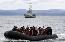 People arrive in a dinghy accompanied by Frontex vessels, on the Greek island of Lesbos