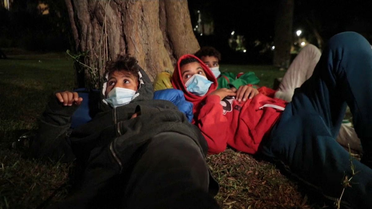 Tres niños migrantes tratan de dormir bajo un árbol en un parque de Ceuta
