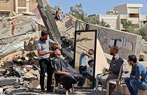 هاشم الجروشة، حلاق فلسطيني يعمل وسط أنقاض مبان ومتاجر دمرتها الغارات الإسرائيلية  في مدينة غزة. 25 مايو 2021.