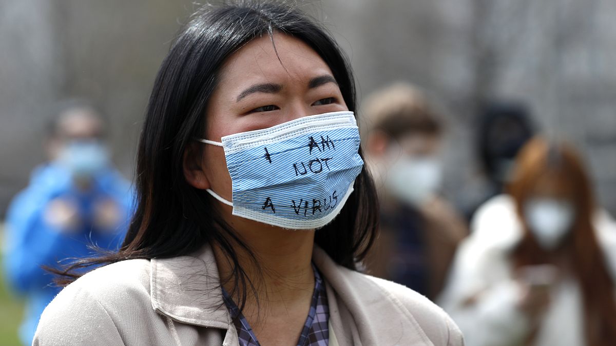 شابة ذات ملامح آسيوية تلبس كمامة كتب عليها "لست فيروساً" 