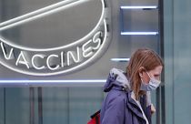 Una mujer con una máscara contra el coronavirus pasa por delante de un cartel de neón en el Instituto Wellcome de Londres, el martes 2 de febrero de 2021.