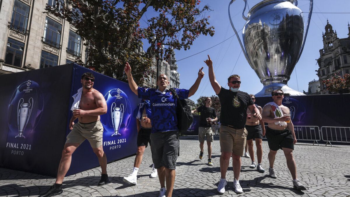Chelsea supporters walk past a giant replica of the Champions League trophy in downtown Porto
