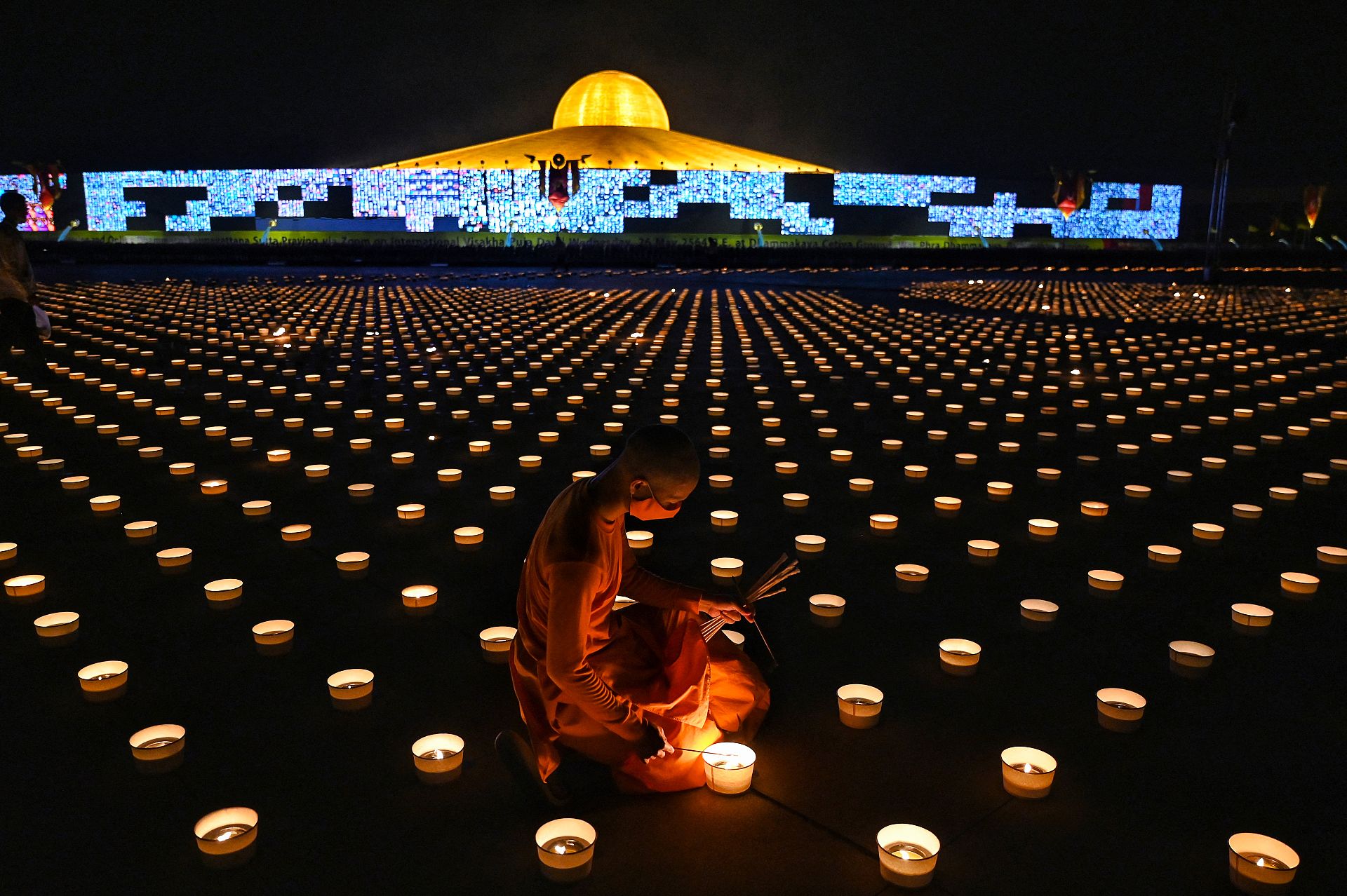 A Buddhist monk lights candles to commemorate Visakha Bucha Day, a celebration of the birth, enlightenment and death of Buddha at a Buddhist temple in Bangkok, Thailand