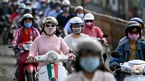 مواطنون فيتناميون يضعون كامات على وجوههم وهم على دراجاتهم في طريقهم إلى العمل وسط العاصمة هانوي