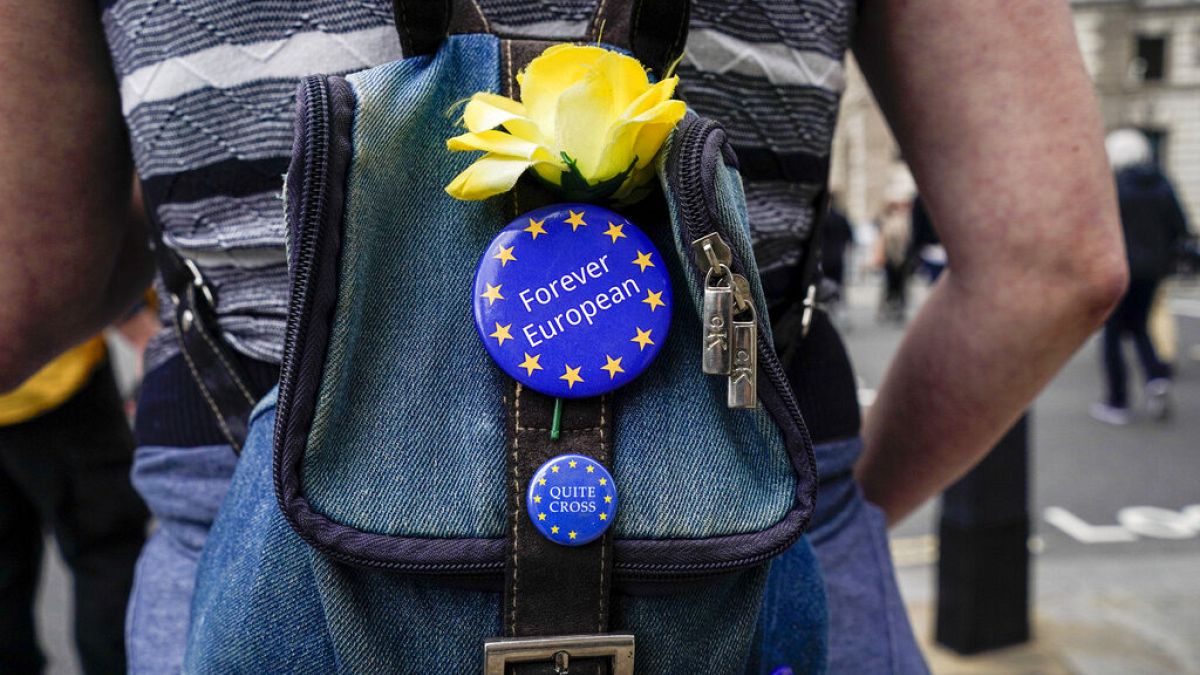 Egy Brexit-ellenes tüntető EU-s jelvényeket visel a táskáján a Parlament tér közelében, Londonban, 2021-ben