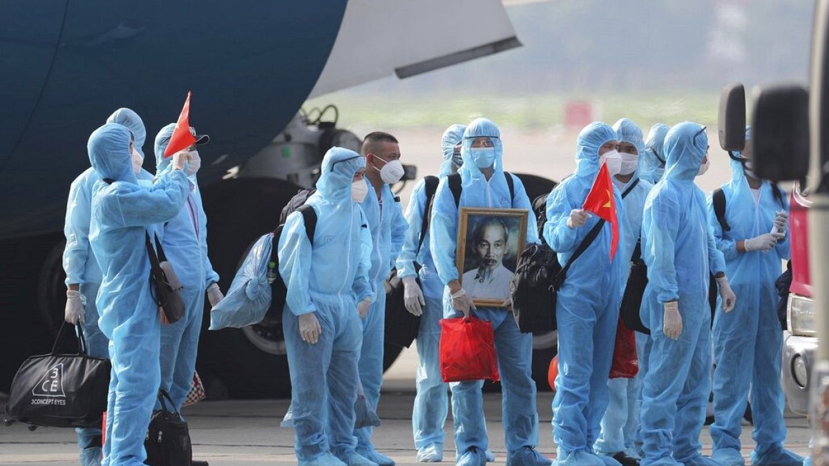 Vietnamese COVID-19 patients in protective gear arrive at Noi Bai airport in Hanoi, Vietnam, in July 2020.