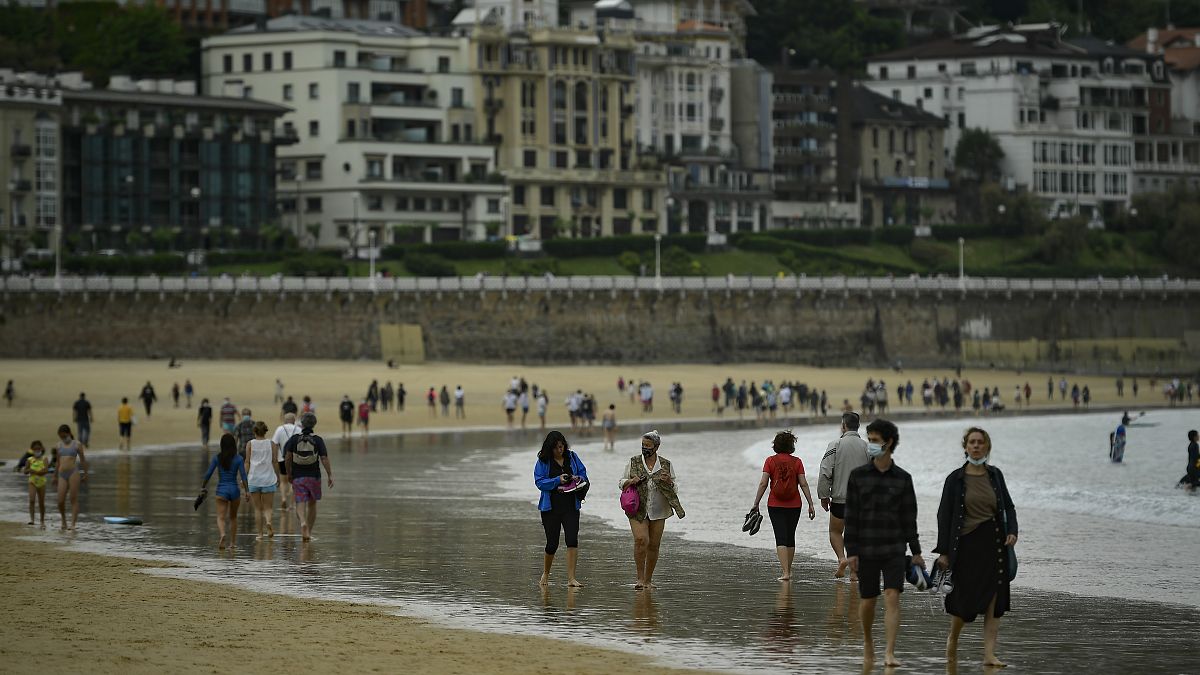 أشخاص يسيرون على طول شاطئ لا كونشا، بعد رفع قيود الإغلاق ، في سان سيباستيان ، شمال إسبانيا ، الأحد 9 مايو 2021.