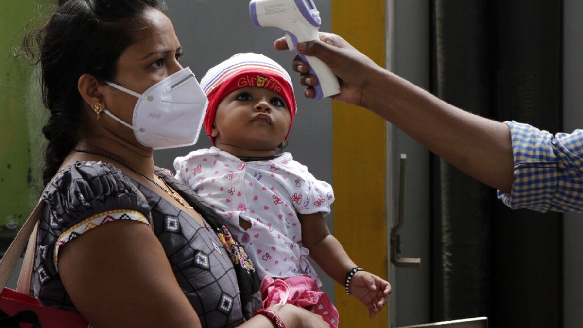 Un sanitario toma la temperatura a una mujer en Bombay, India