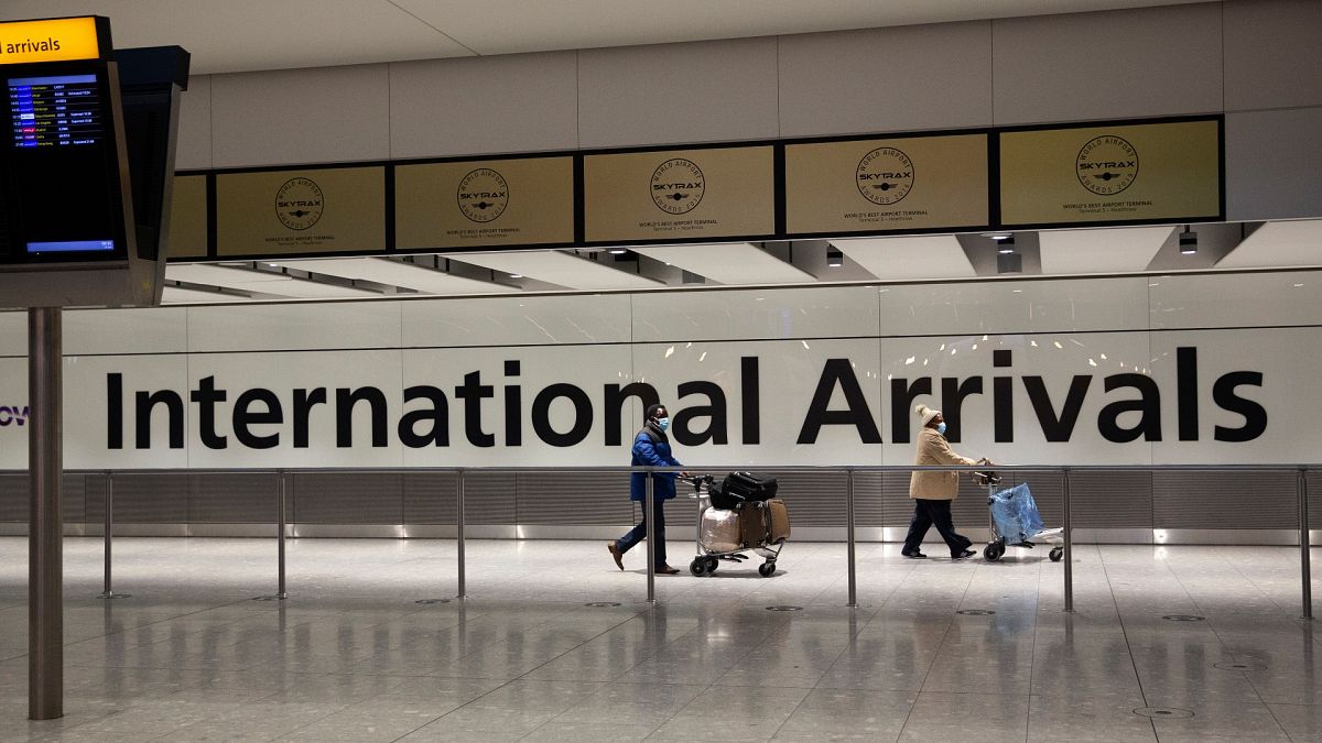 Arriving passengers walk past a sign in the arrivals area at Heathrow Airport in London, on Jan. 26, 2021.