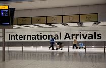 Arriving passengers walk past a sign in the arrivals area at Heathrow Airport in London, on Jan. 26, 2021.