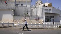 Damasco 2011: un agente pattuglia l'ingresso dell'ambasciata statunitense, danneggiata da manifestanti pro-governativi