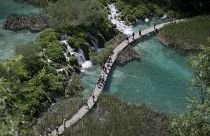 In this photo taken June 21, 2013, tourists walk across a bridge in the national park Plitvice, central Croatia. In this photo taken June 21, 2013, tourists walk across a bridge in the national park Plitvice, central Croatia.