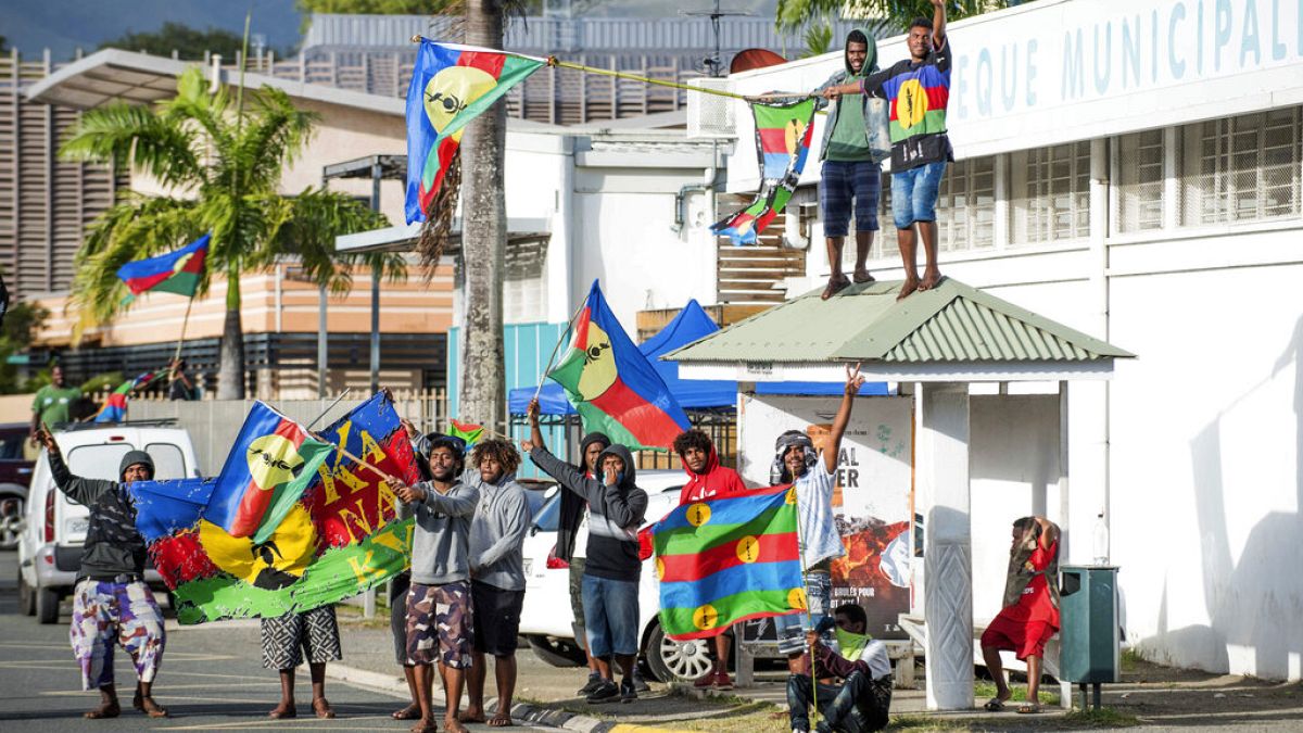 Apoiantes da independência manifestam-se com a bandeira Kanak à porta de uma assembleia de voto no distrito de Riviere Salee, em Noumea, Nova Caledónia, no domingo, 4 de outubro de 2020 AP Photo/Mathurin 